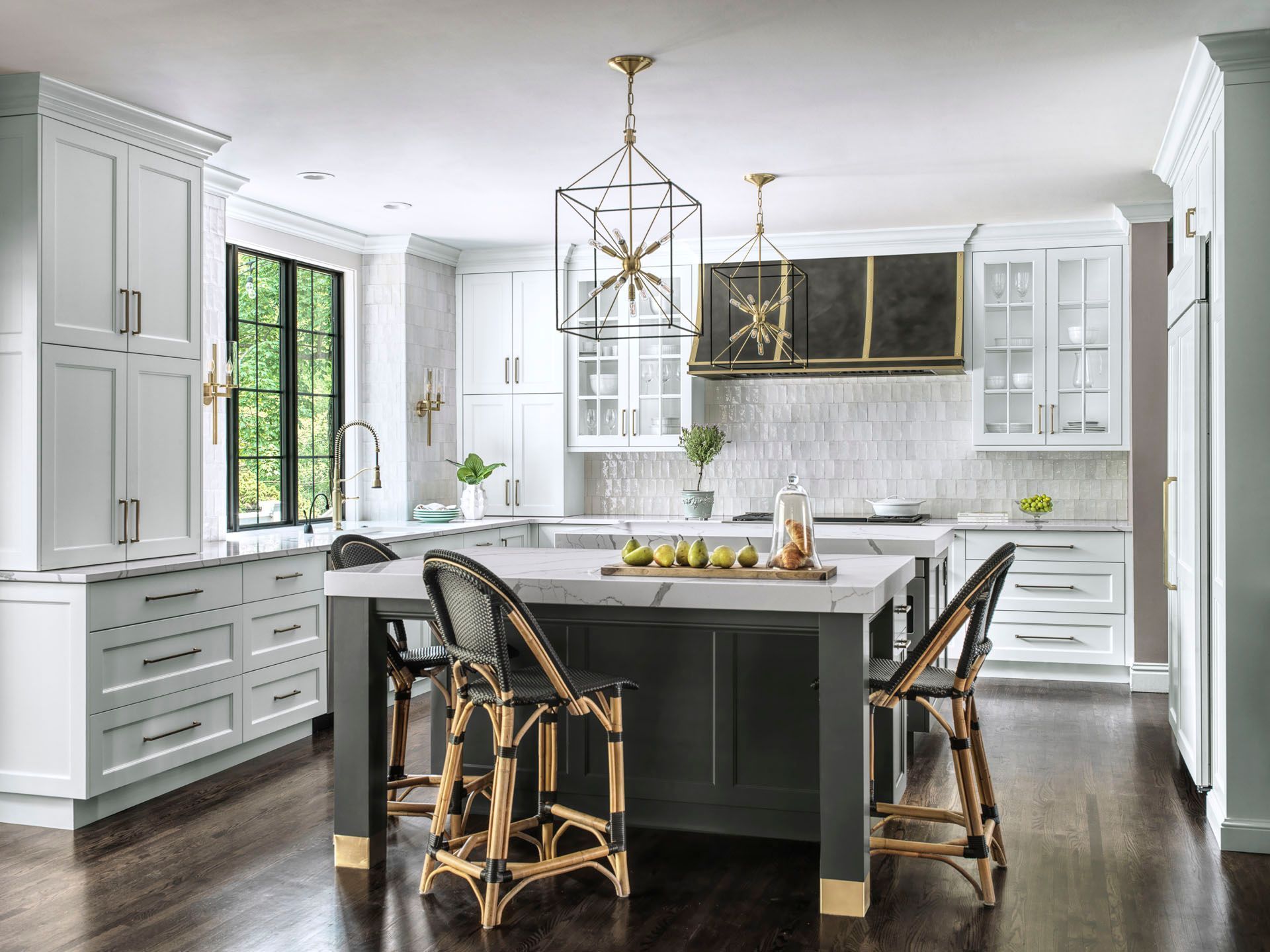 Bright white modern kitchen with a large island, black chairs, and gold pendant lights