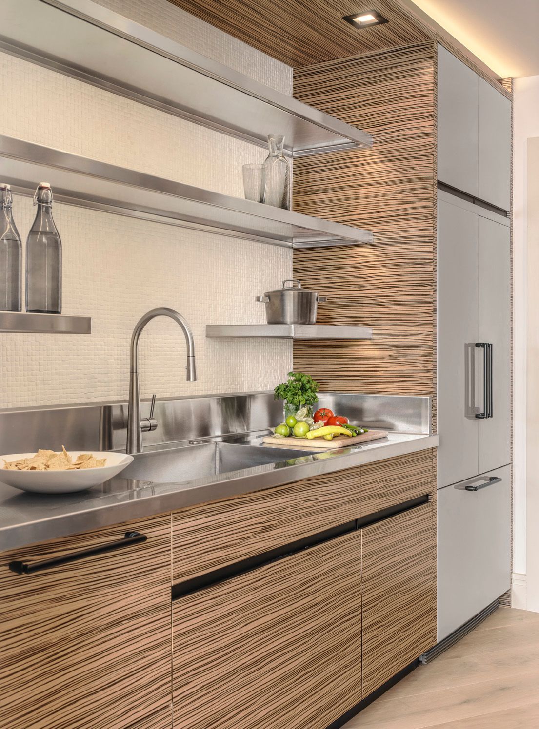 Modern kitchen with stainless sink, open shelves, woven wood cabinets, and a tall fridge.