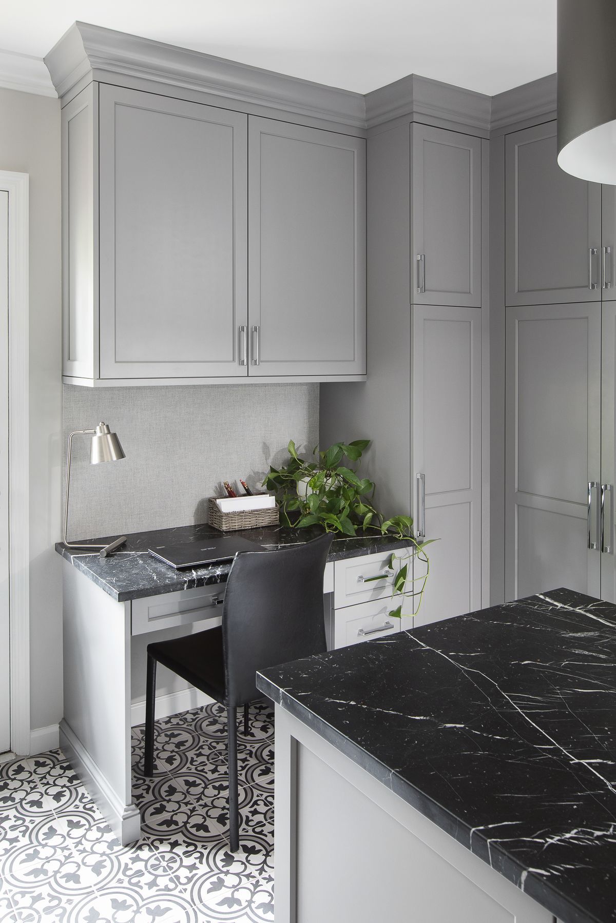 Modern kitchen with gray cabinets, black marble island, and a small sink and table by the wal.