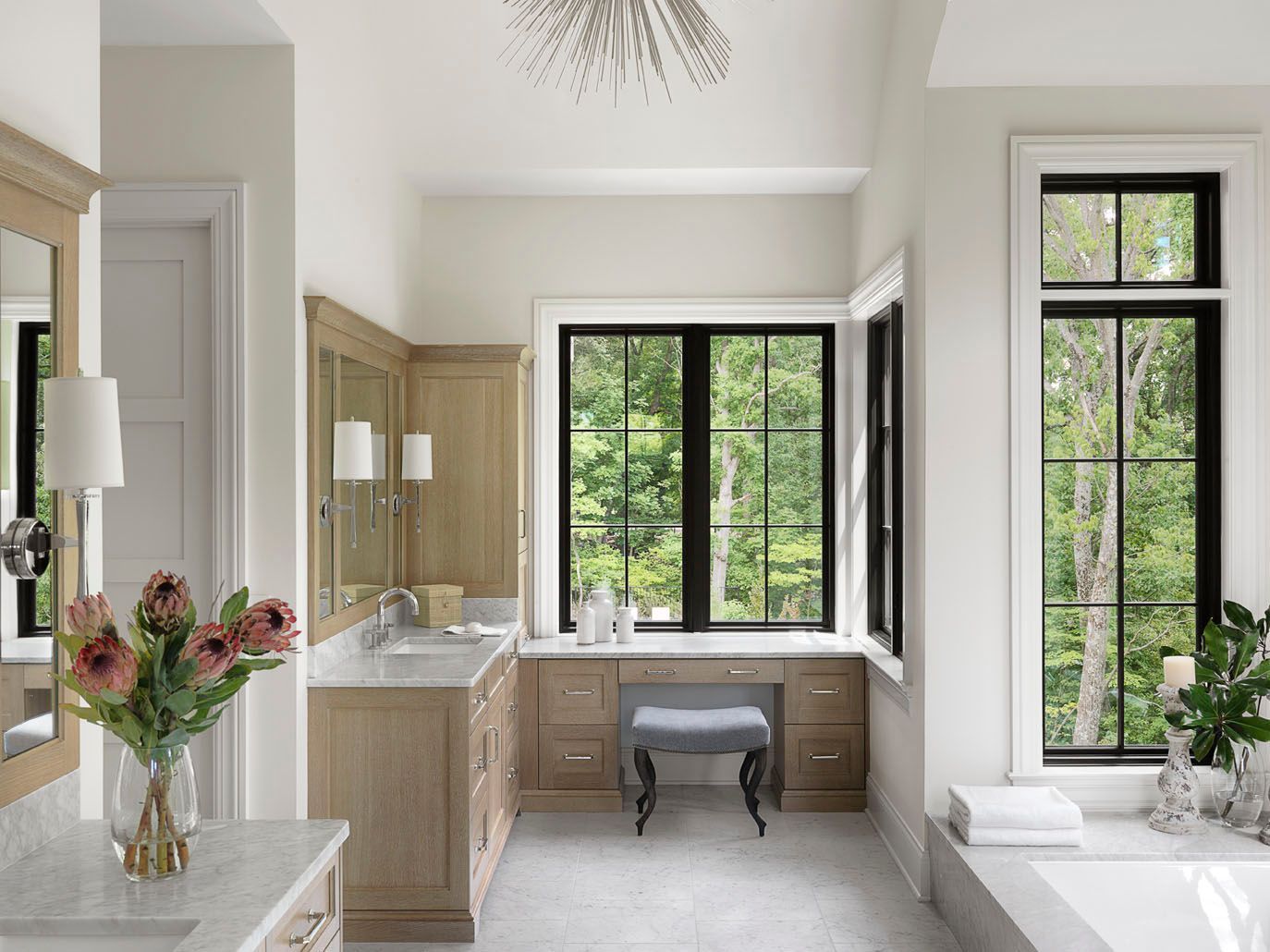 Bright bathroom with wood vanity, large windows, and white freestanding tub