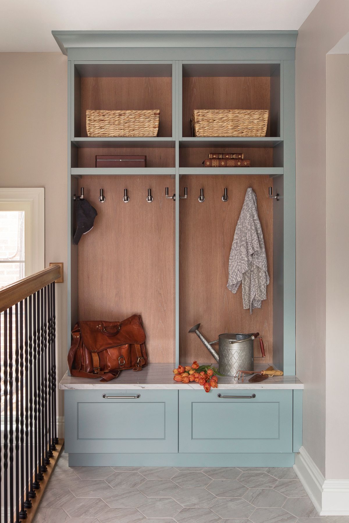 Built-in mudroom bench with hooks, cubbies, and light blue storage cabinets in a hallway