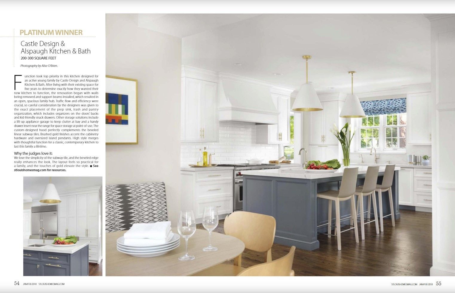 A bright kitchen with white cabinetry, dark grey island, hardwood floors, dining table, and two pendant lights.