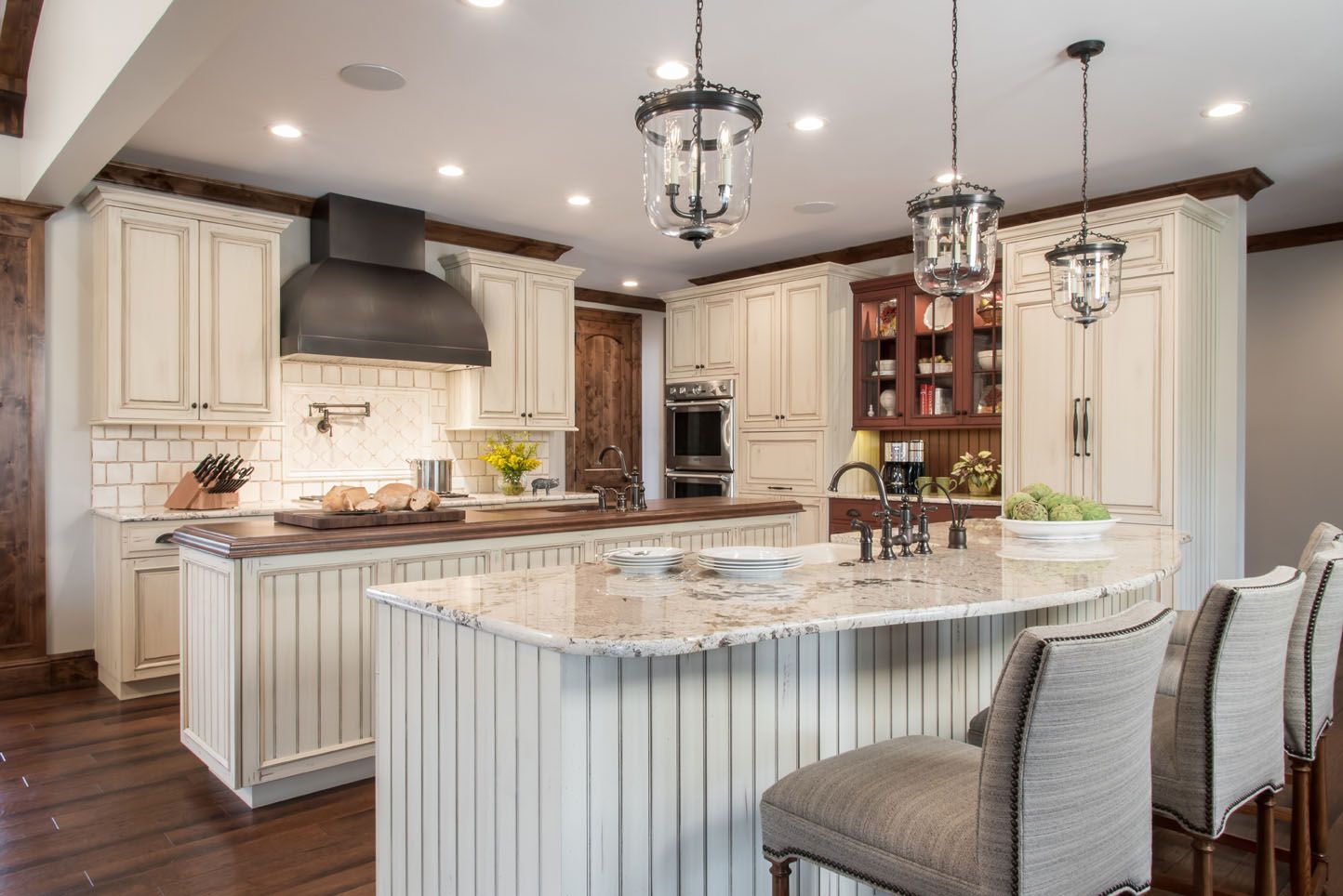 Bright modern kitchen with white cabinets, large island, pendant lights, and gray barstools