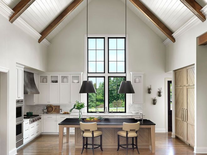 Bright minimalist kitchen-dining room with vaulted ceiling, large window, and a central table with two chairs.