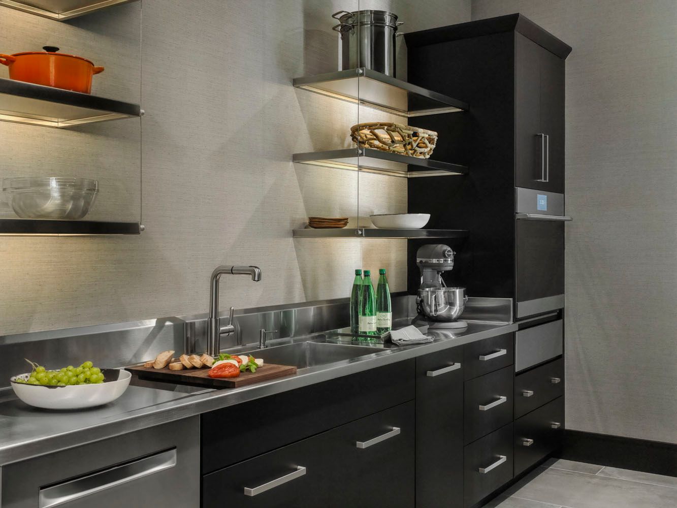 Modern kitchen with black cabinets, stainless steel appliances, countertop dishes, and a bowl of salad.
