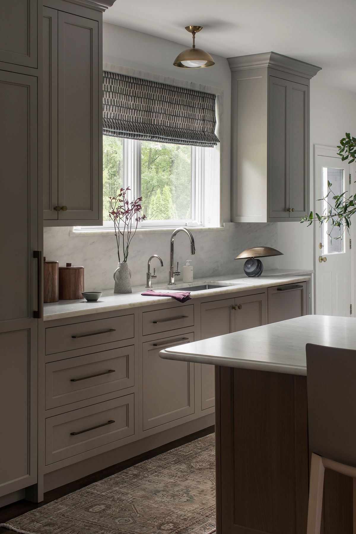 Bright kitchen with gray cabinets, white countertops, and a window above the sink.