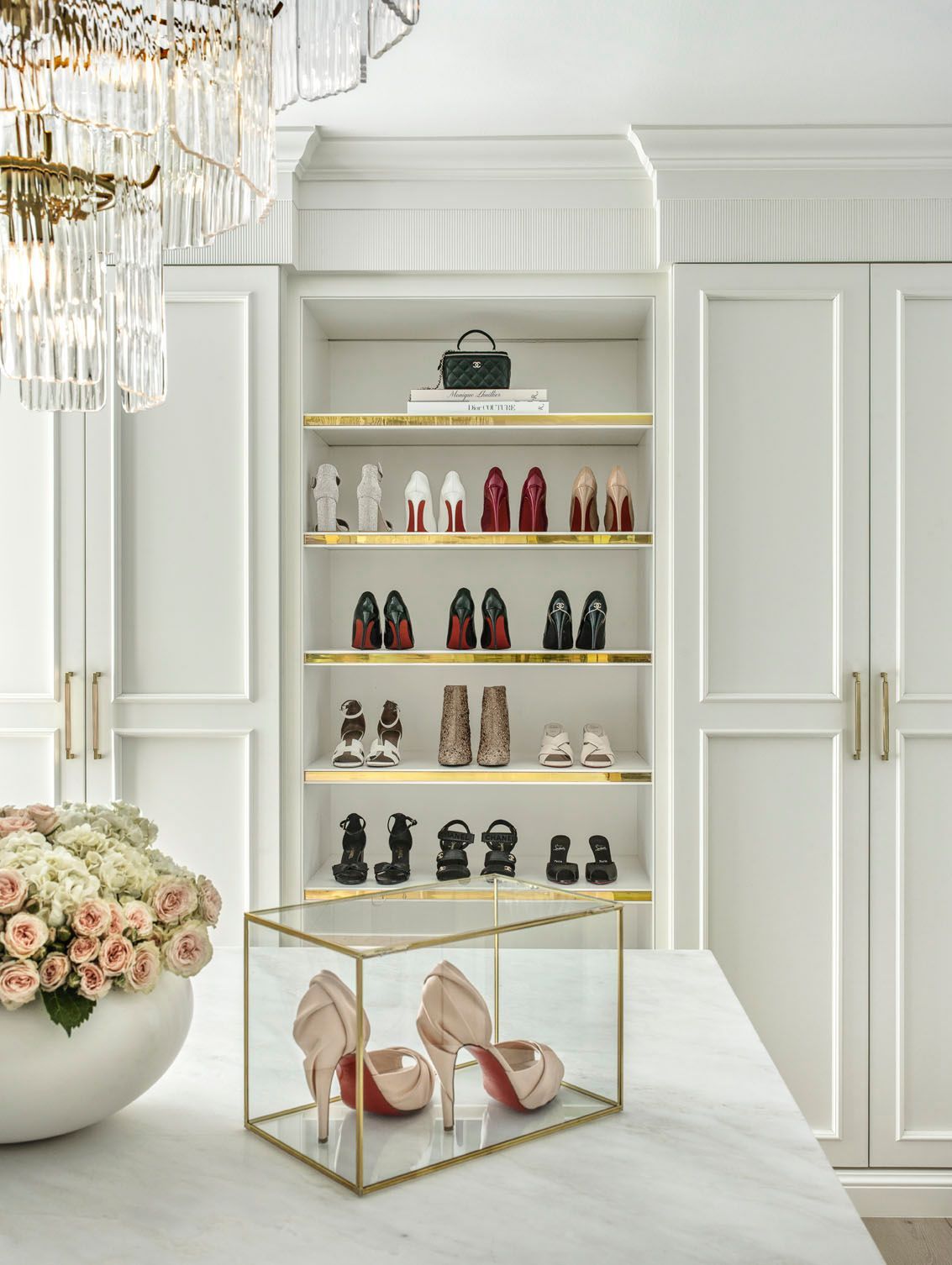 White boutique display cabinet with shoes and handbags on shelves, in a bright elegant room