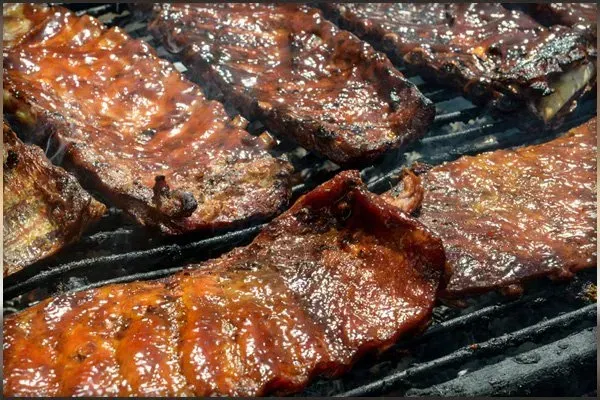 A close up of ribs cooking on a grill