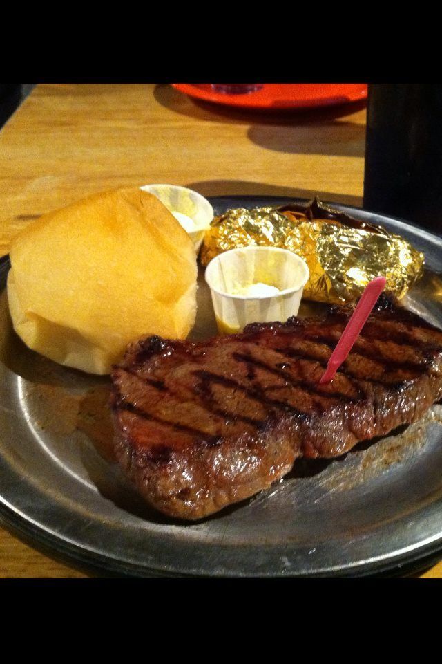 A plate of food with a steak a baked potato and a roll