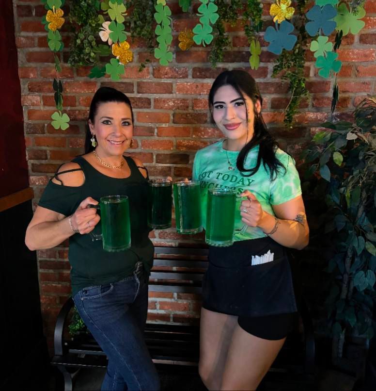 Two women standing next to each other holding green mugs