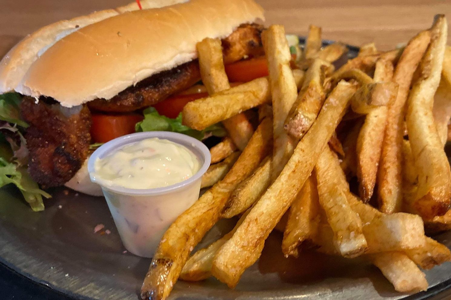 A sandwich and french fries on a plate with a dipping sauce.