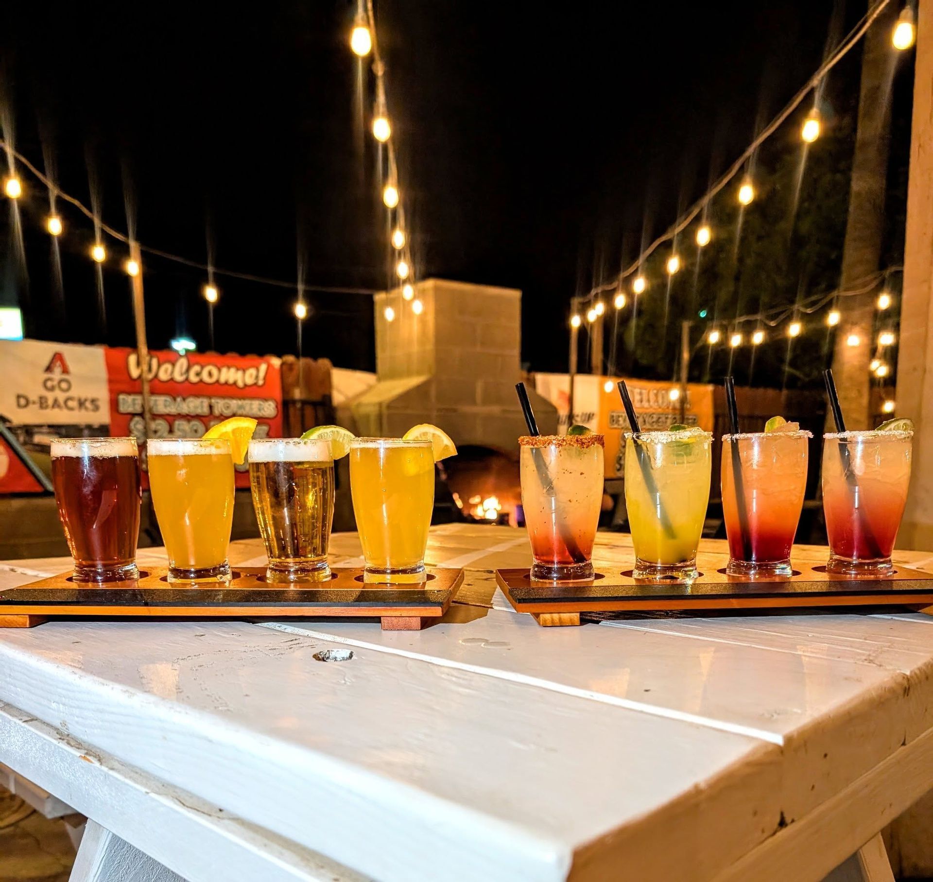 A row of drinks on a table with a welcome sign in the background
