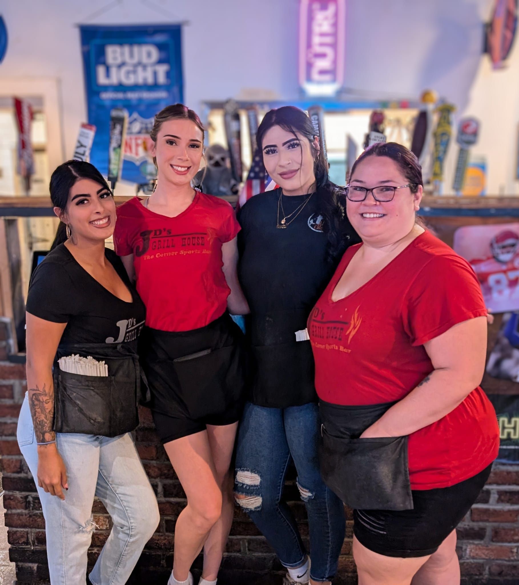 A group of women is posing for a picture in front of a Bud Light sign.