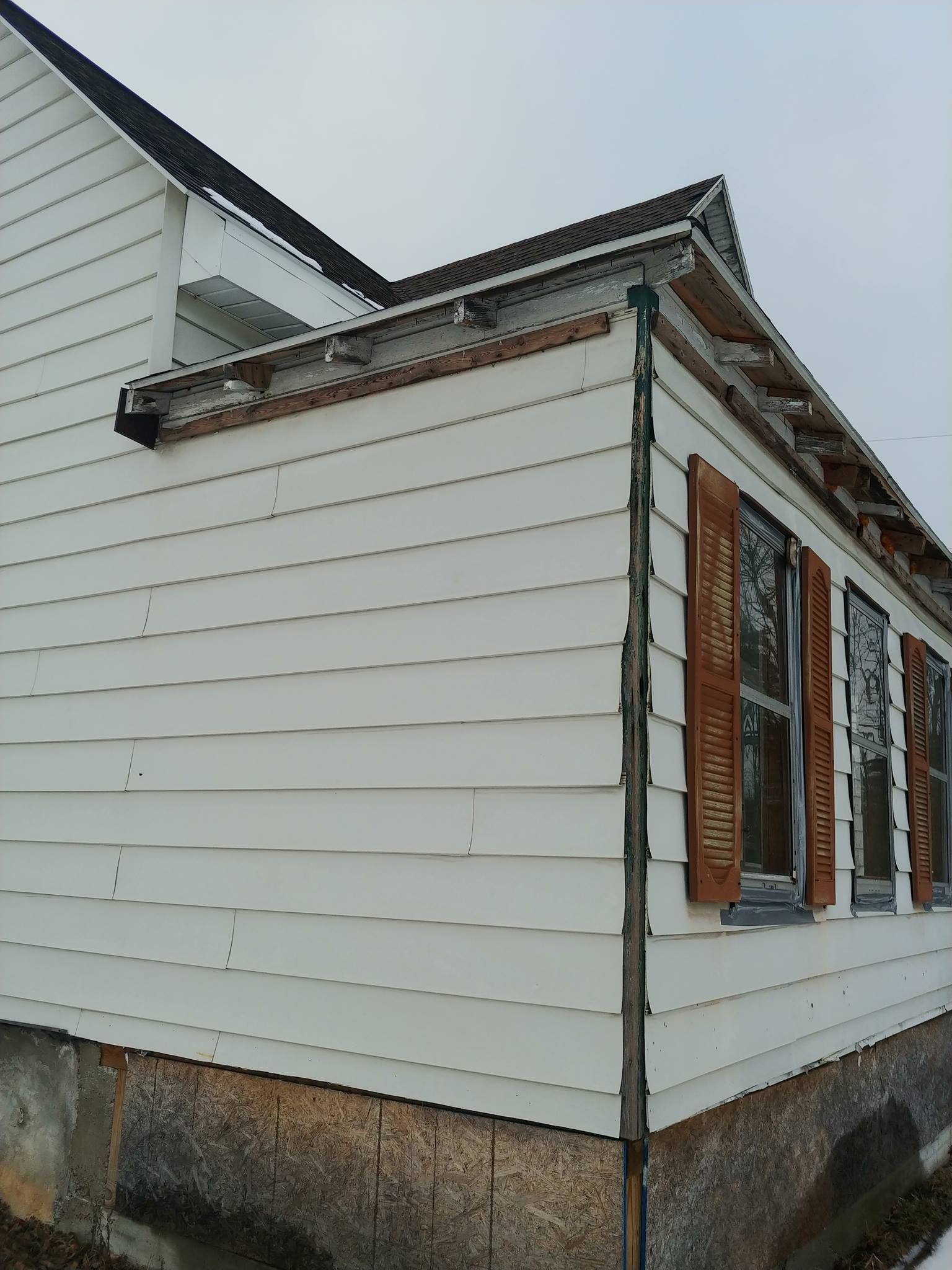 White house with brown shutters on a cloudy day.