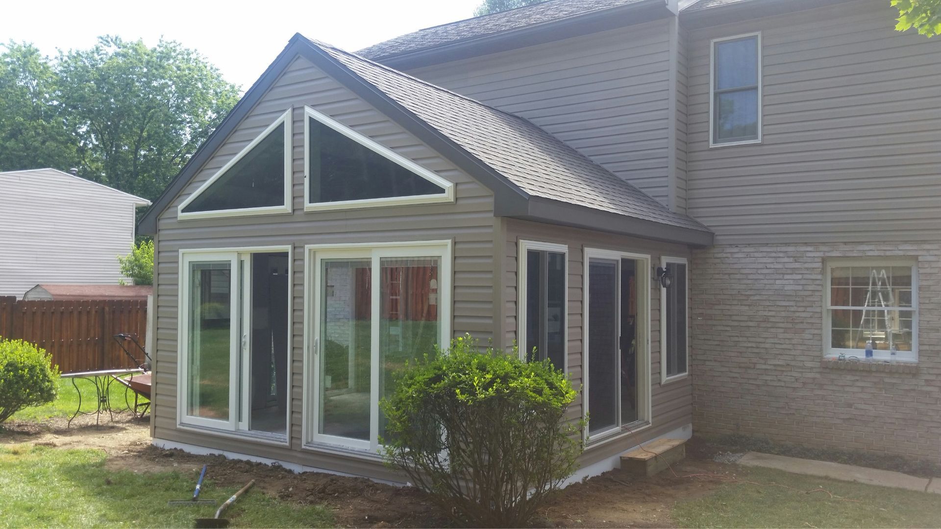 Sunroom addition with large windows and triangle-shaped windows in a light-colored exterior.