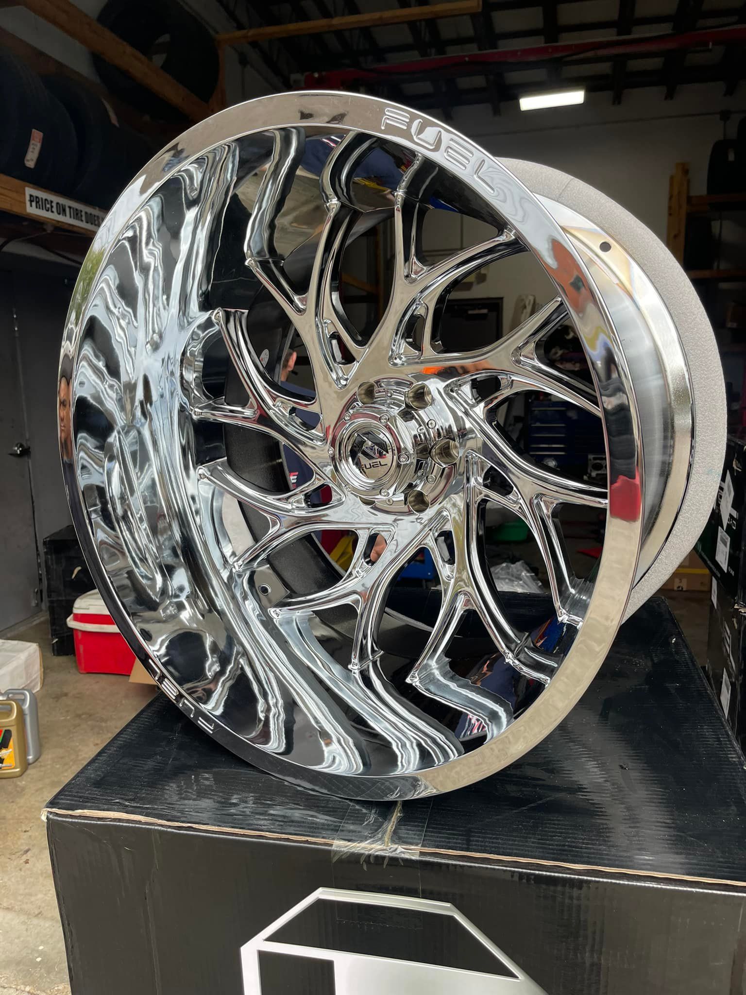 Chrome alloy car wheel on a black box, indoors.