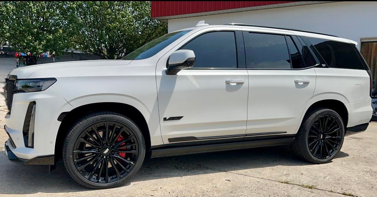 White Cadillac Escalade SUV with black rims parked outdoors.