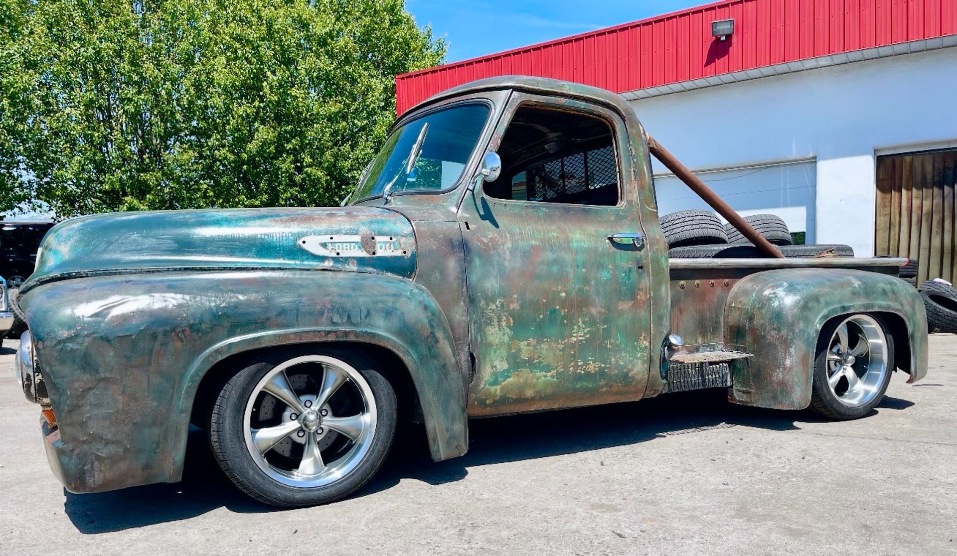 Green and rusty vintage Ford pickup truck with lowered suspension.