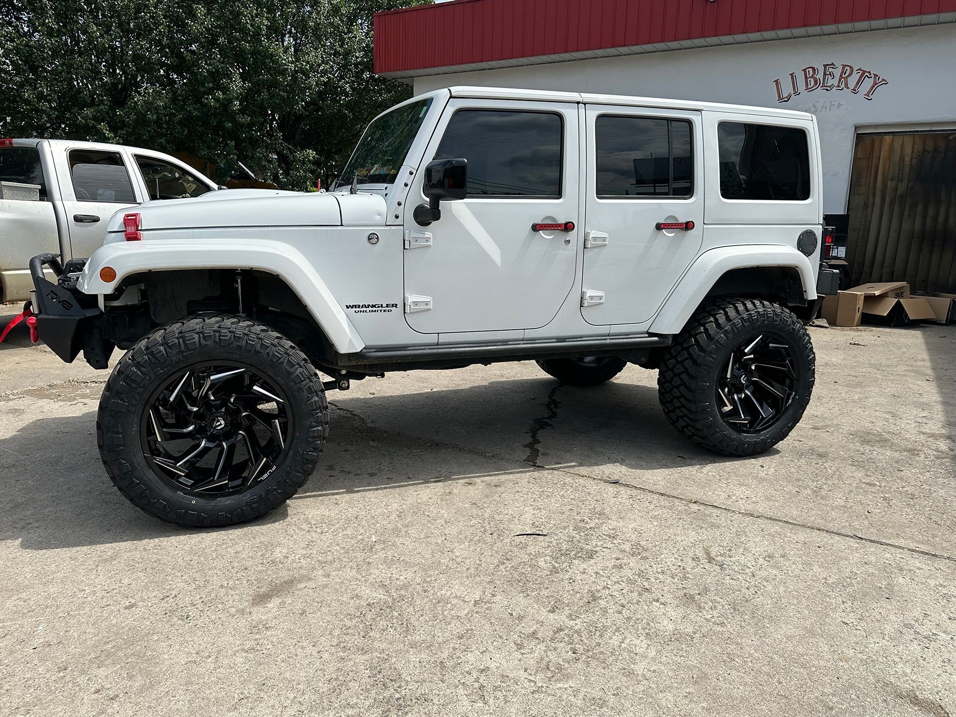 White Jeep Wrangler with black rims parked outside a building.