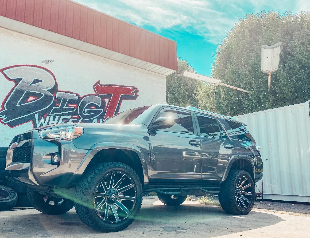 Gray SUV with custom black and chrome rims parked in front of a