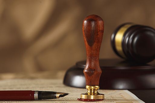 A fountain pen is sitting on a piece of paper next to a wooden judge 's gavel.