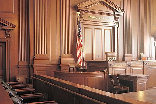 An empty courtroom with an American flag hanging from the ceiling.