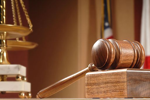 A wooden judge 's gavel is sitting on a wooden block in front of a scale of justice.