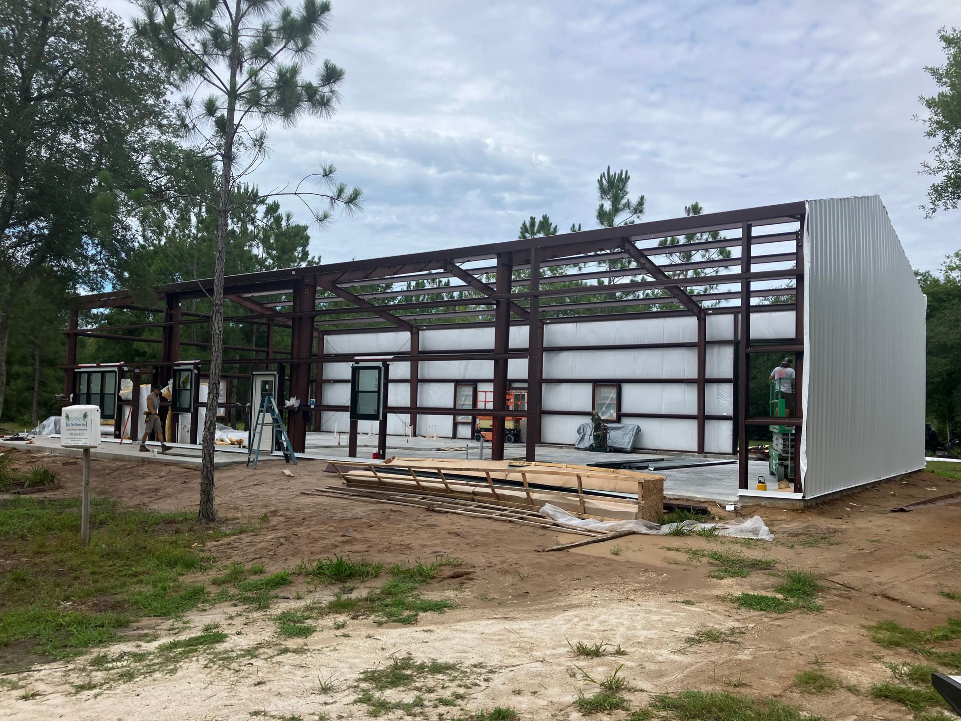 A large metal building is being built in the middle of a field.