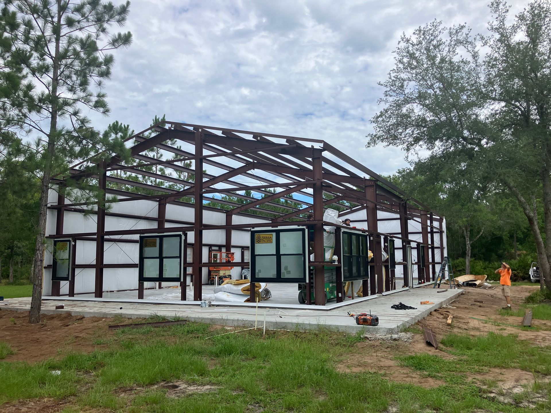A large metal building is being built in the middle of a grassy field.