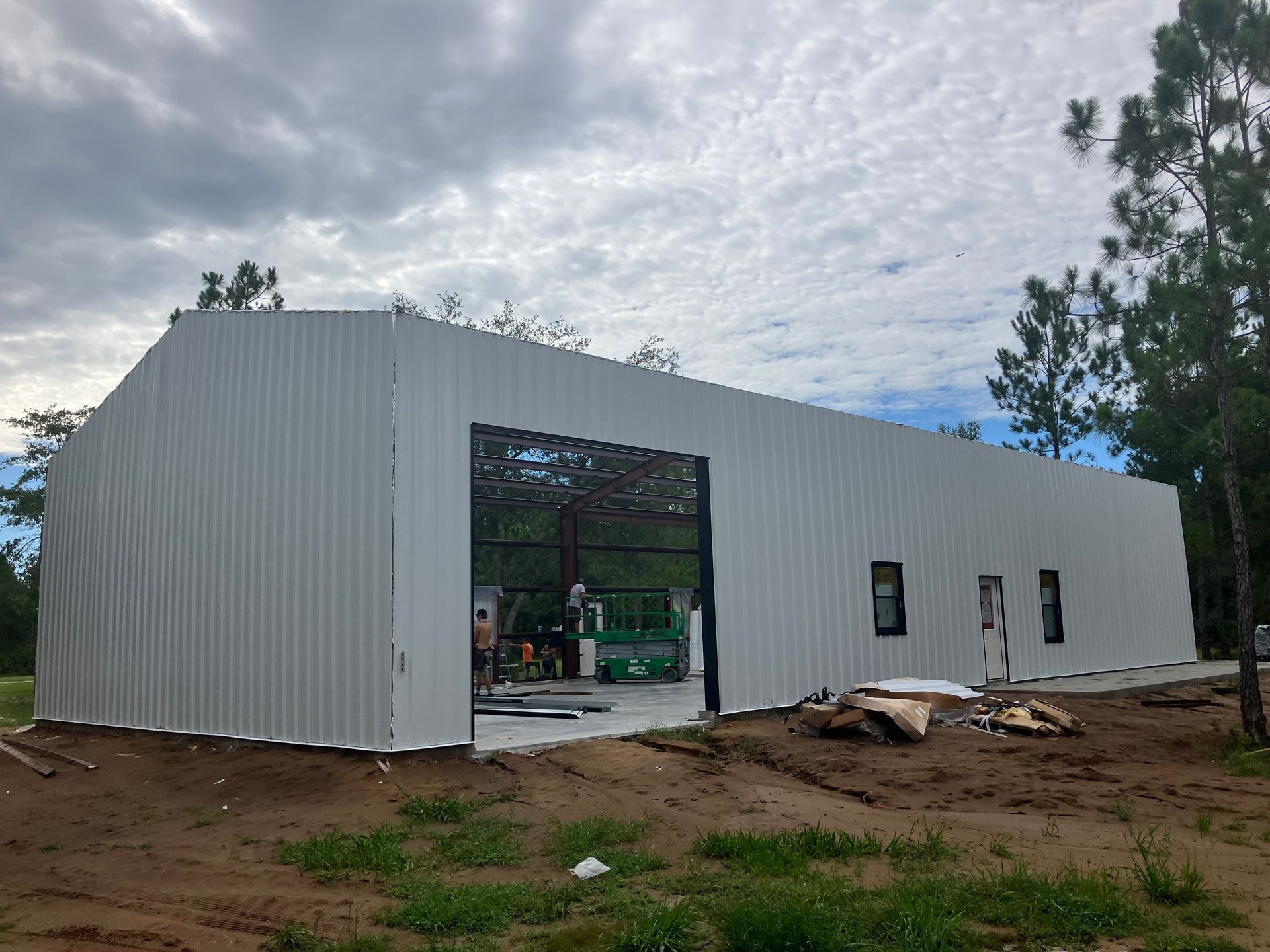 A large white building is being built in the middle of a field.