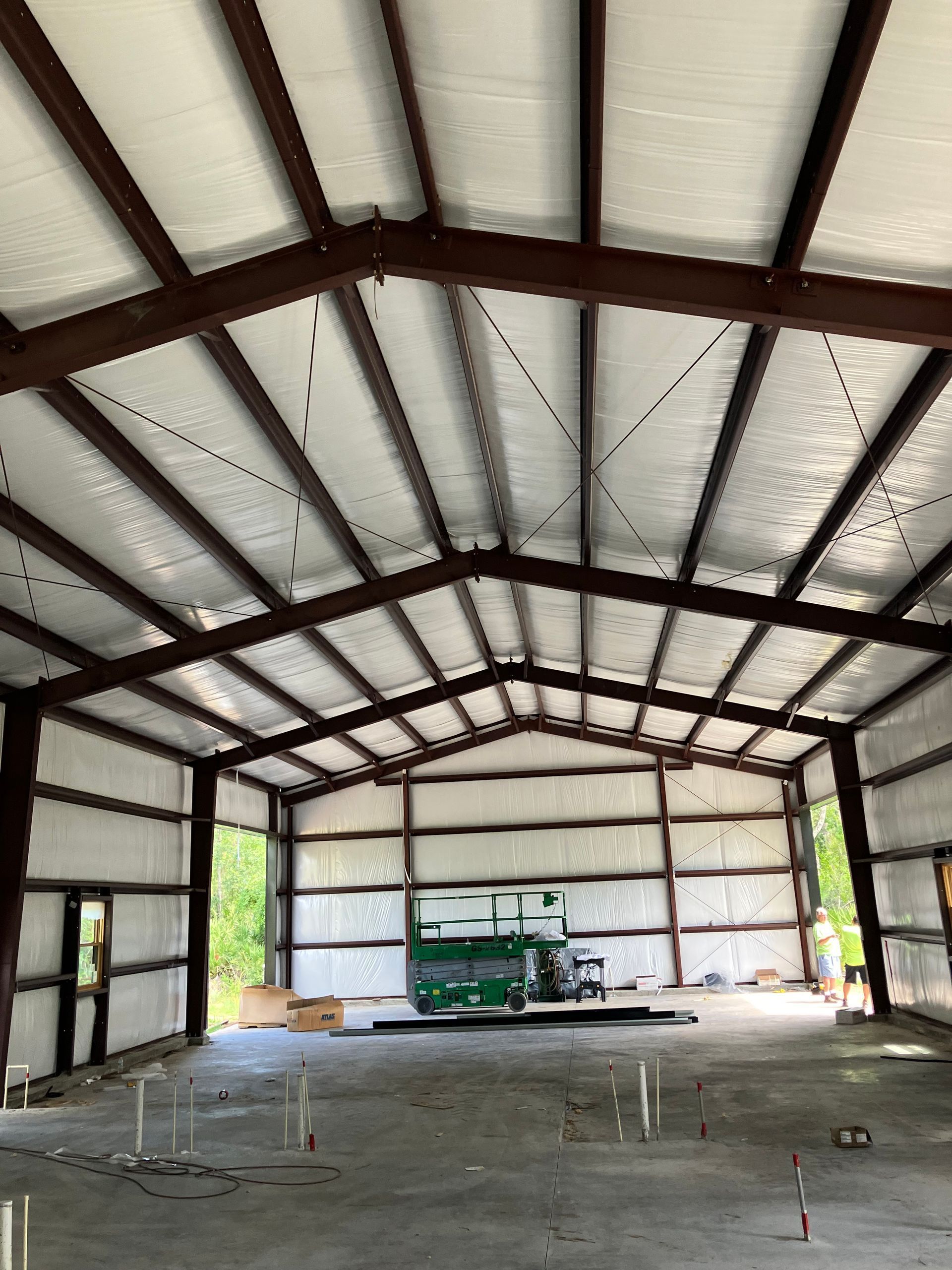 A large metal building with a green truck parked inside of it.