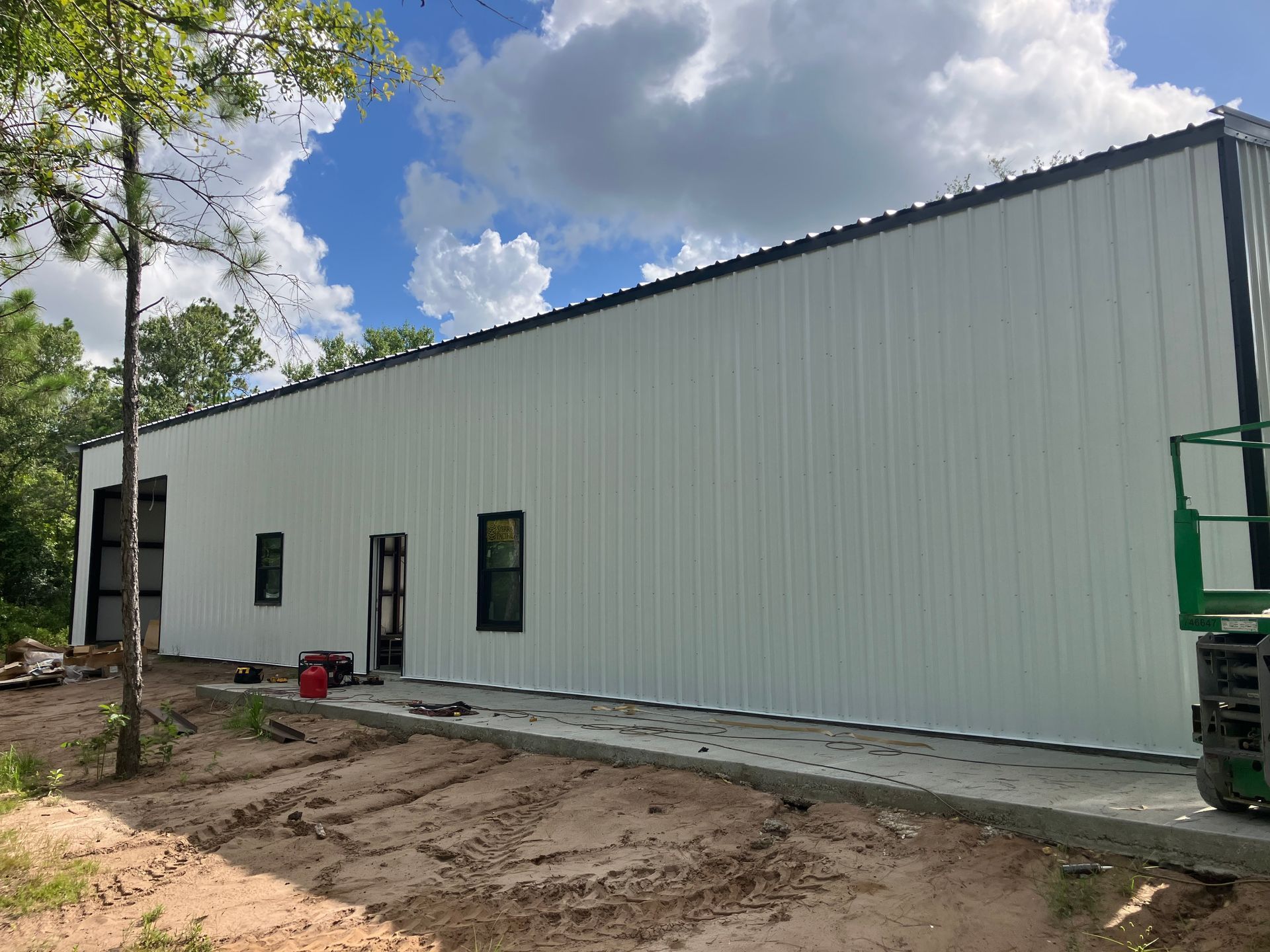 A large white building is being built in the middle of a dirt field.