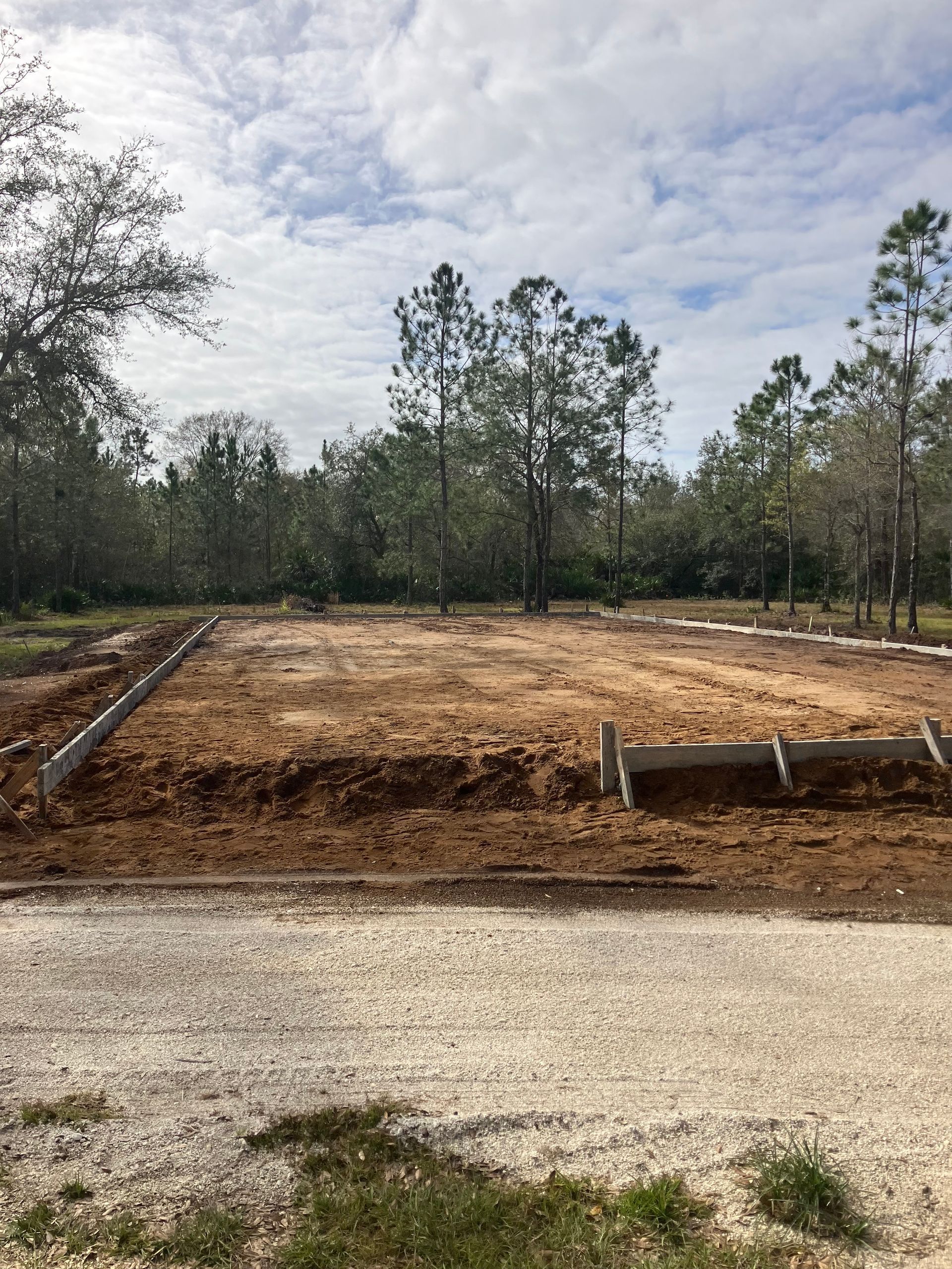 A dirt field with trees in the background and a blue sky in the background.