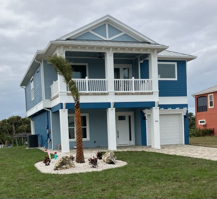 A blue and white house with a palm tree in front of it