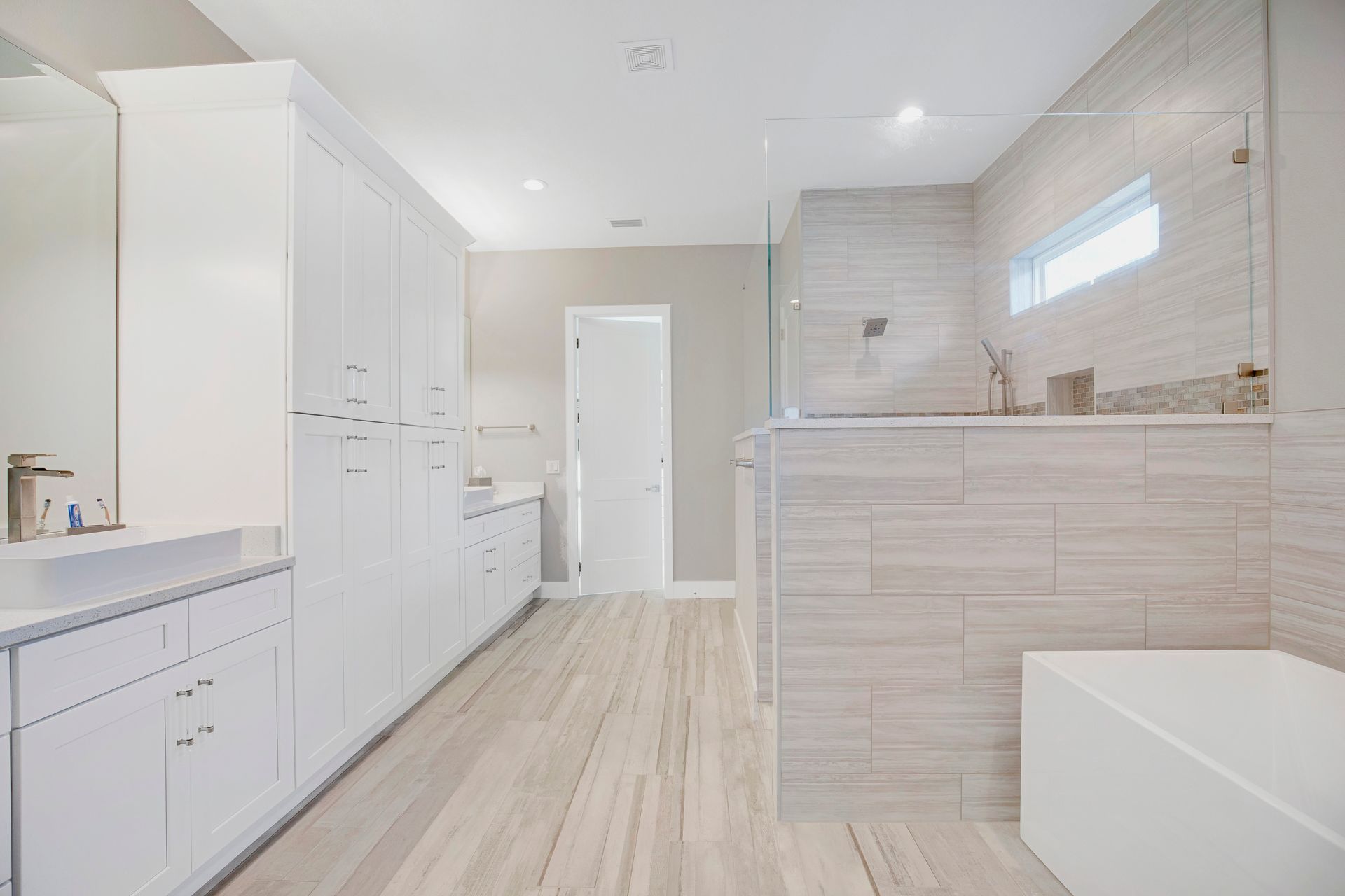 A bathroom with two sinks, a tub, and a walk in shower.