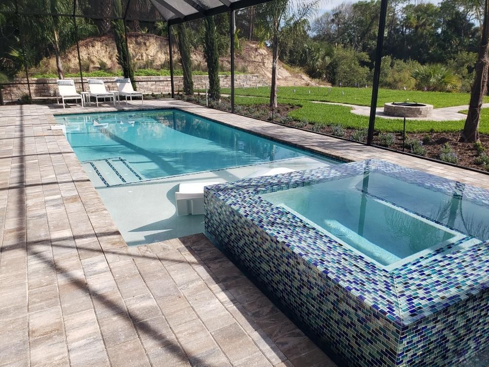 A large swimming pool with a hot tub next to it.