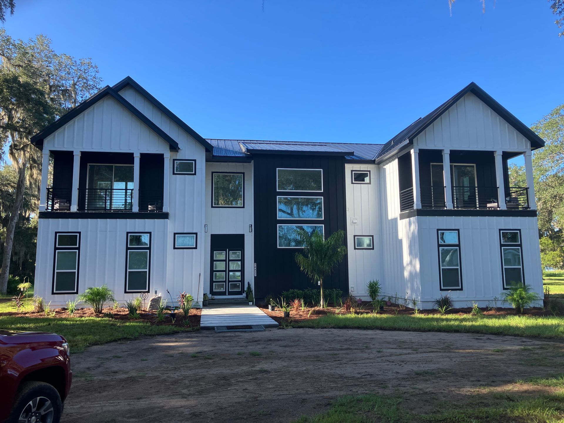 A large white and black house with a red truck parked in front of it.