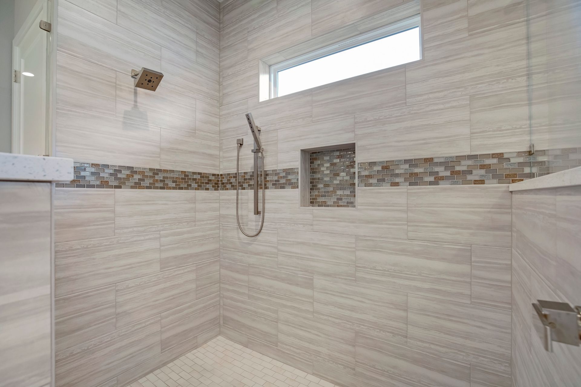 A bathroom with a walk in shower and a window.