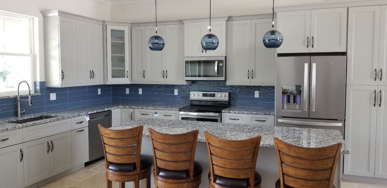 A kitchen with white cabinets, granite counter tops, stainless steel appliances and a large island.