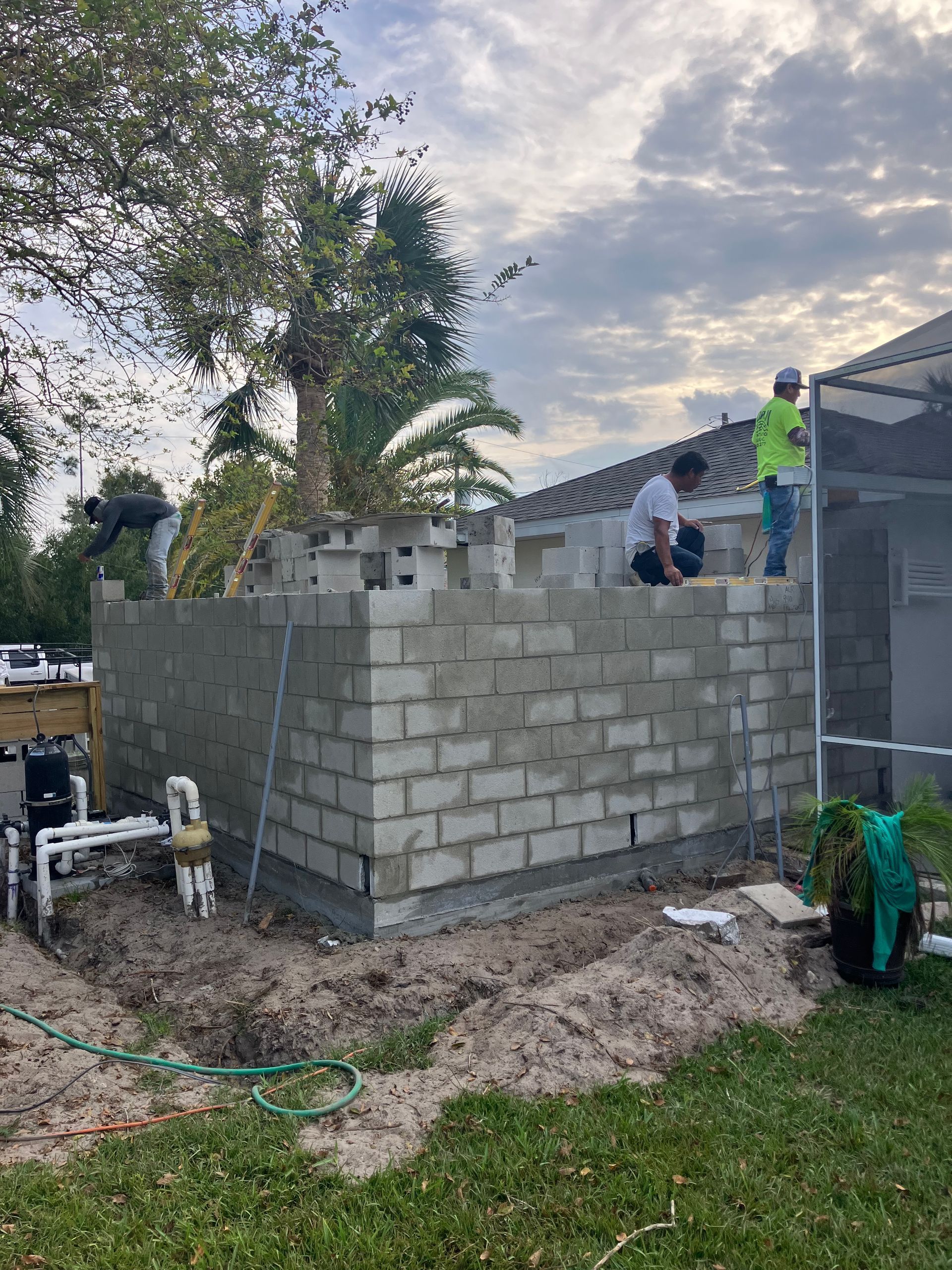 A couple of men are sitting on top of a brick wall.