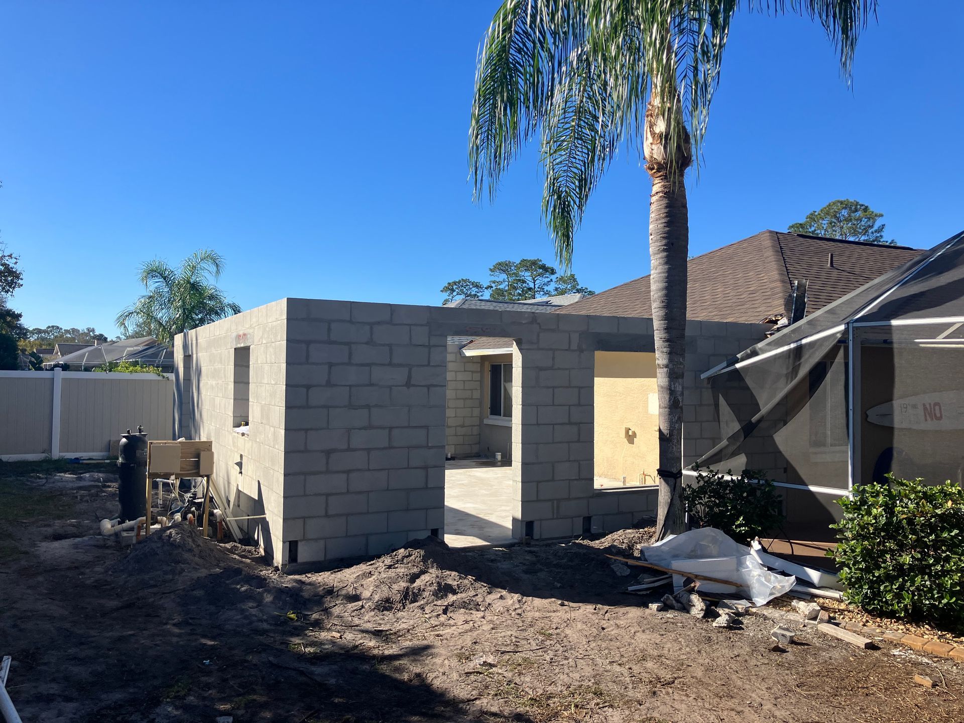 A house is being built with bricks and a palm tree in the background.