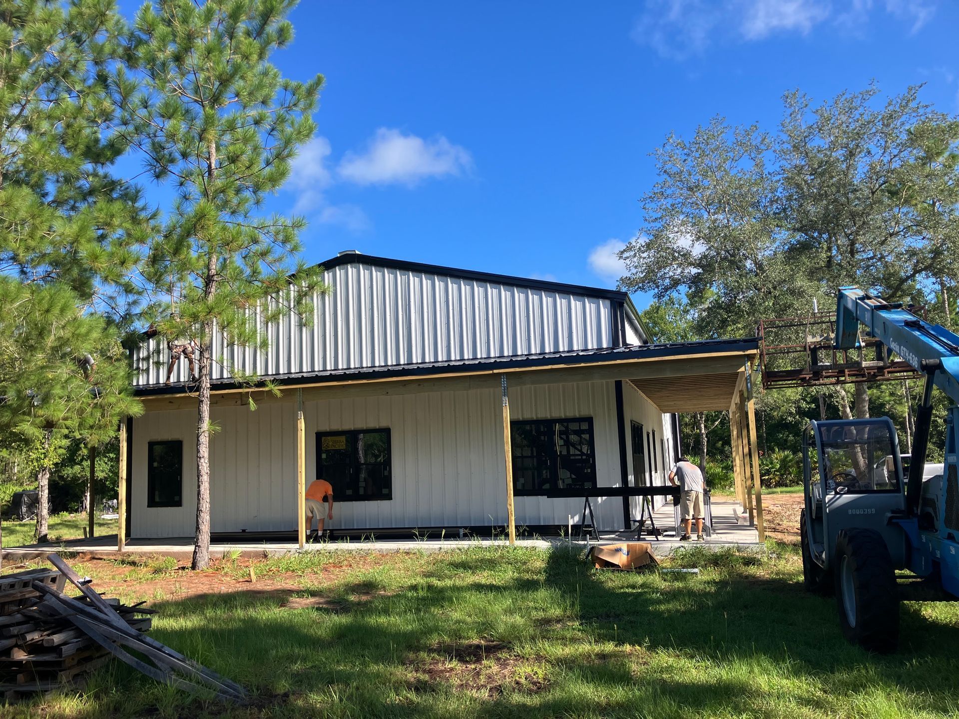 A large metal building with a garage door is sitting in the middle of a dirt field.