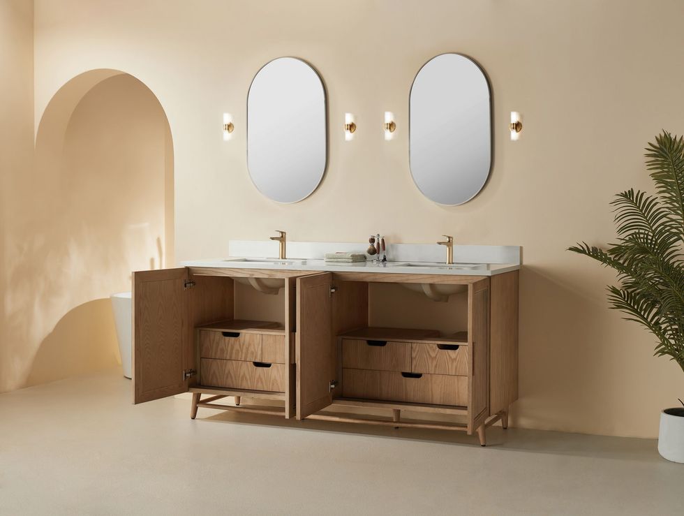 Modern beige bathroom with double sinks, oval mirrors, wall sconces, and open wooden cabinets