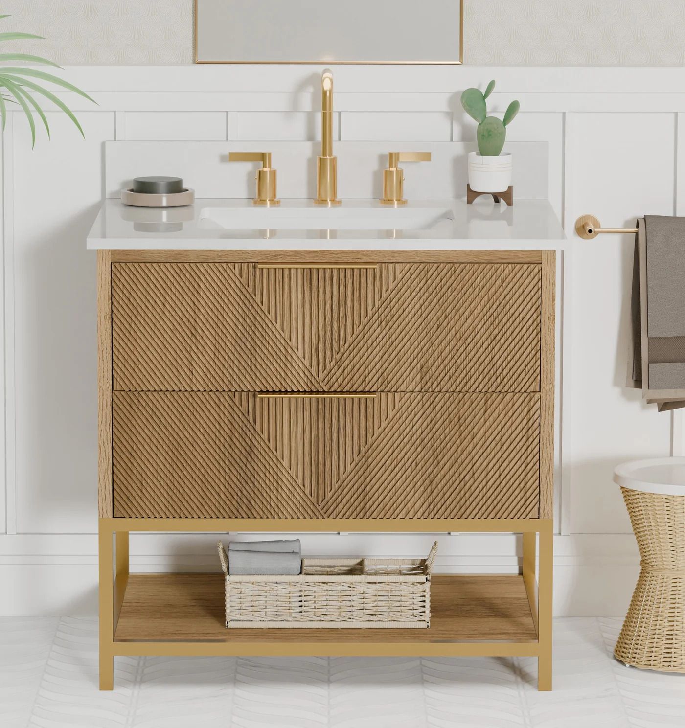 White-and-gold bathroom vanity with woven front, gold faucet, and towels on a wicker basket sink stand