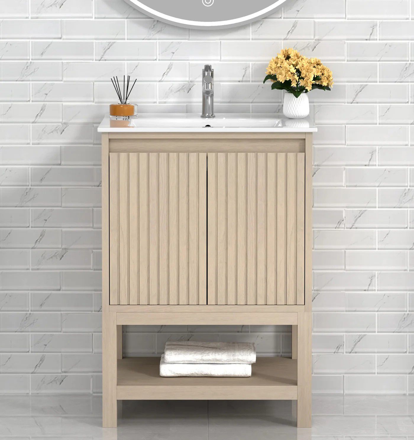 Beige vanity cabinet with sink in a white tiled bathroom, styled with flowers and towels.