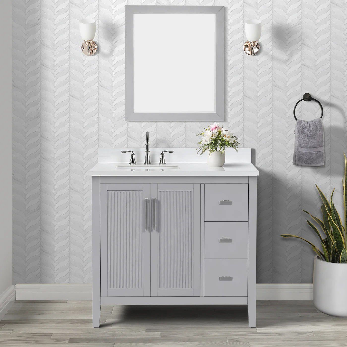 Gray bathroom vanity with mirror, sink, wall sconces, towel ring, and potted plant