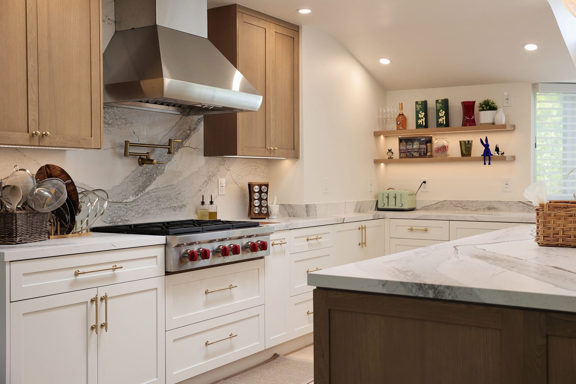 Bright modern white kitchen with marble island, stainless range hood, and open shelves