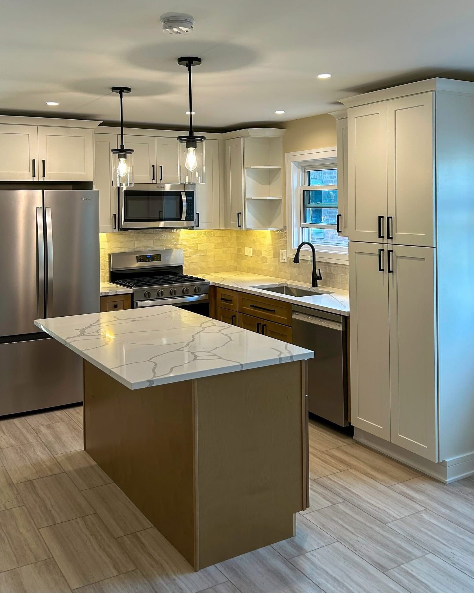 Modern kitchen with stainless steel appliances, white cabinets, island, and warm under-cabinet lighting