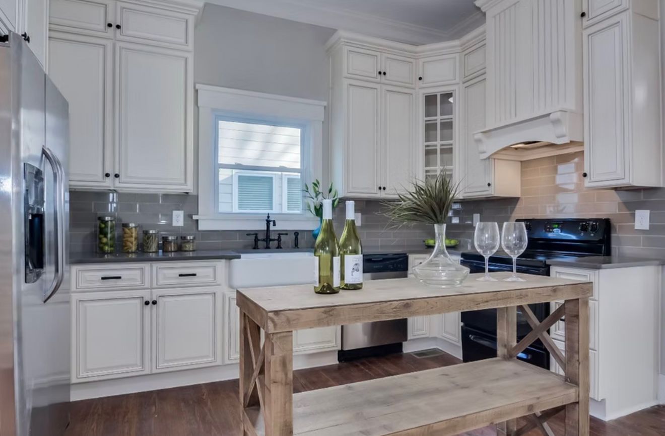 Bright white kitchen with farmhouse island, cabinets, window, and countertop decor