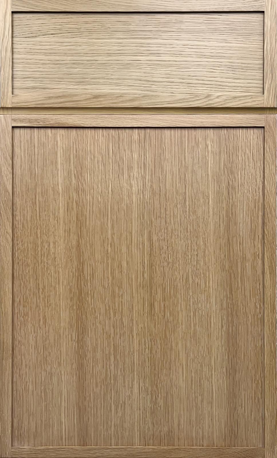 Wooden cabinet door with a small drawer panel above, in light oak finish